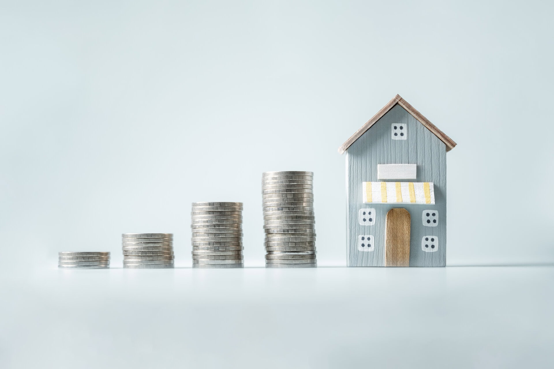 property management concept. real estate investment. planning estate business. housing market agent. a house is shown with a stack of coins on top of it. the coins are arranged in a pyramid shape.