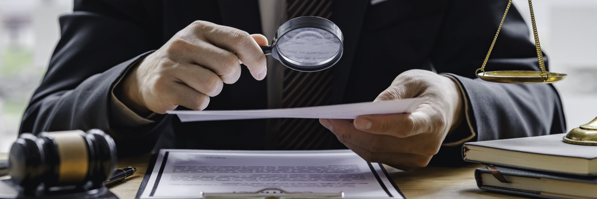 Attorney or judge sitting at  desk, holding magnifying glass and reading book. Businessman, business auditor, teacher, professor searching for information, fact-checking, law consulting professional