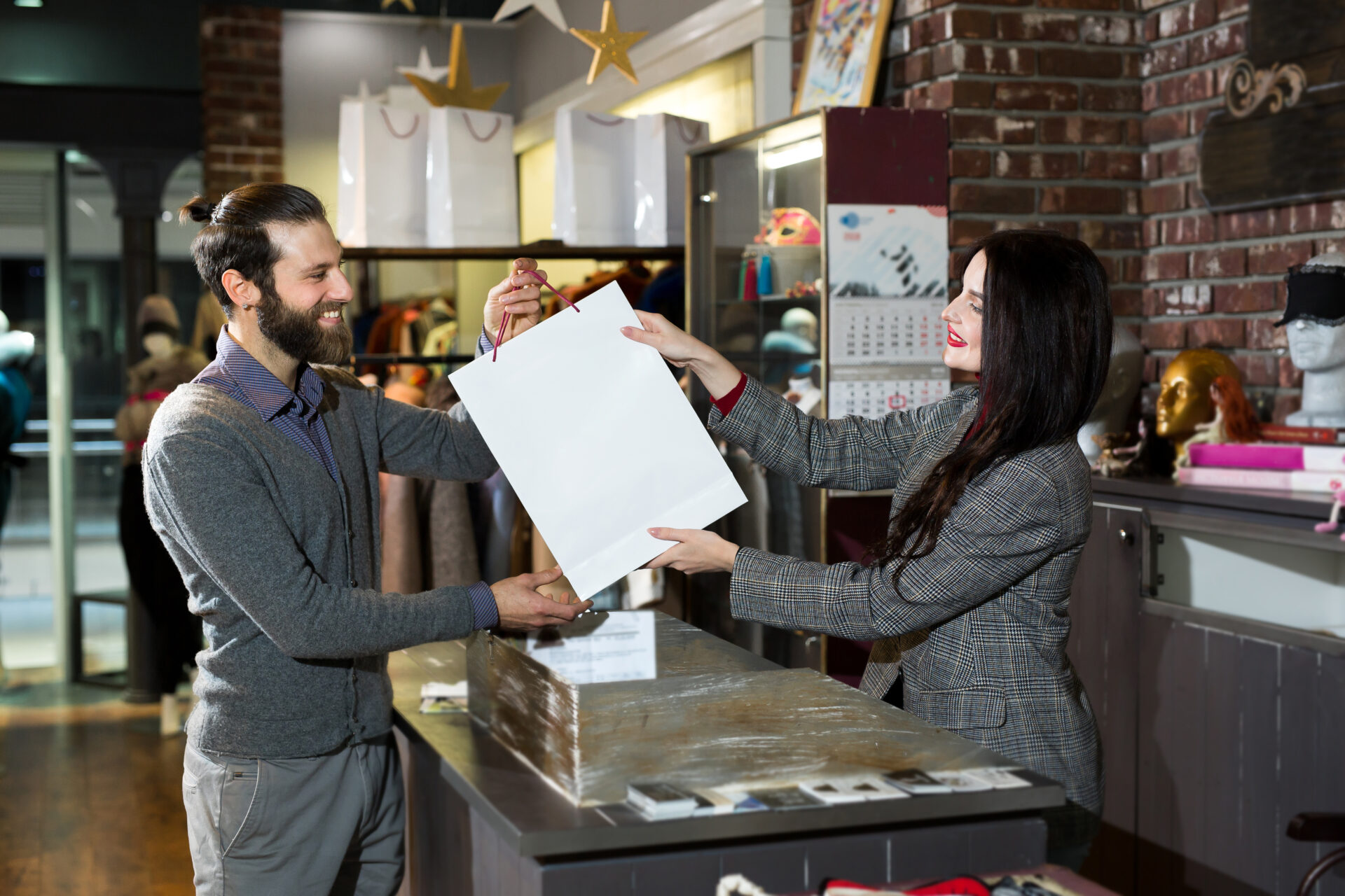 attractive saleswoman, handing over a bag of clothes to a beautiful couple of men and women.