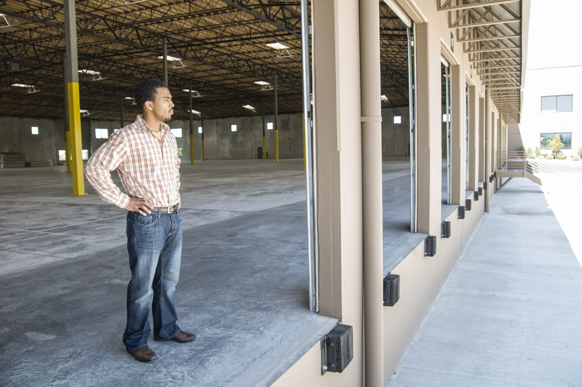 black man standing in loading dock door of new empty warehouse anticipating the arrival of the first truck load new business.