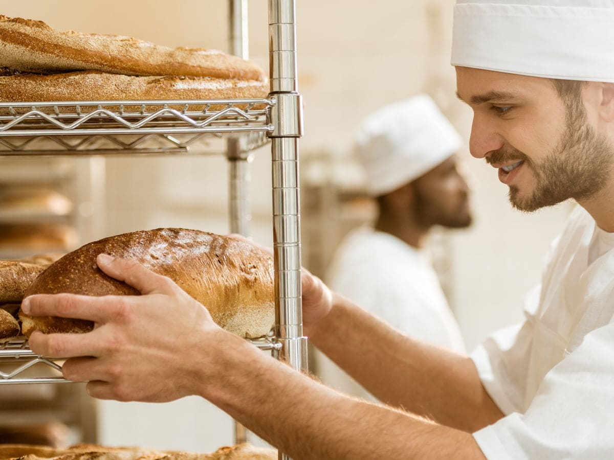 cheerful baker arranging bread in commercial baker 2026 03 13 01 07 38 utc (1)