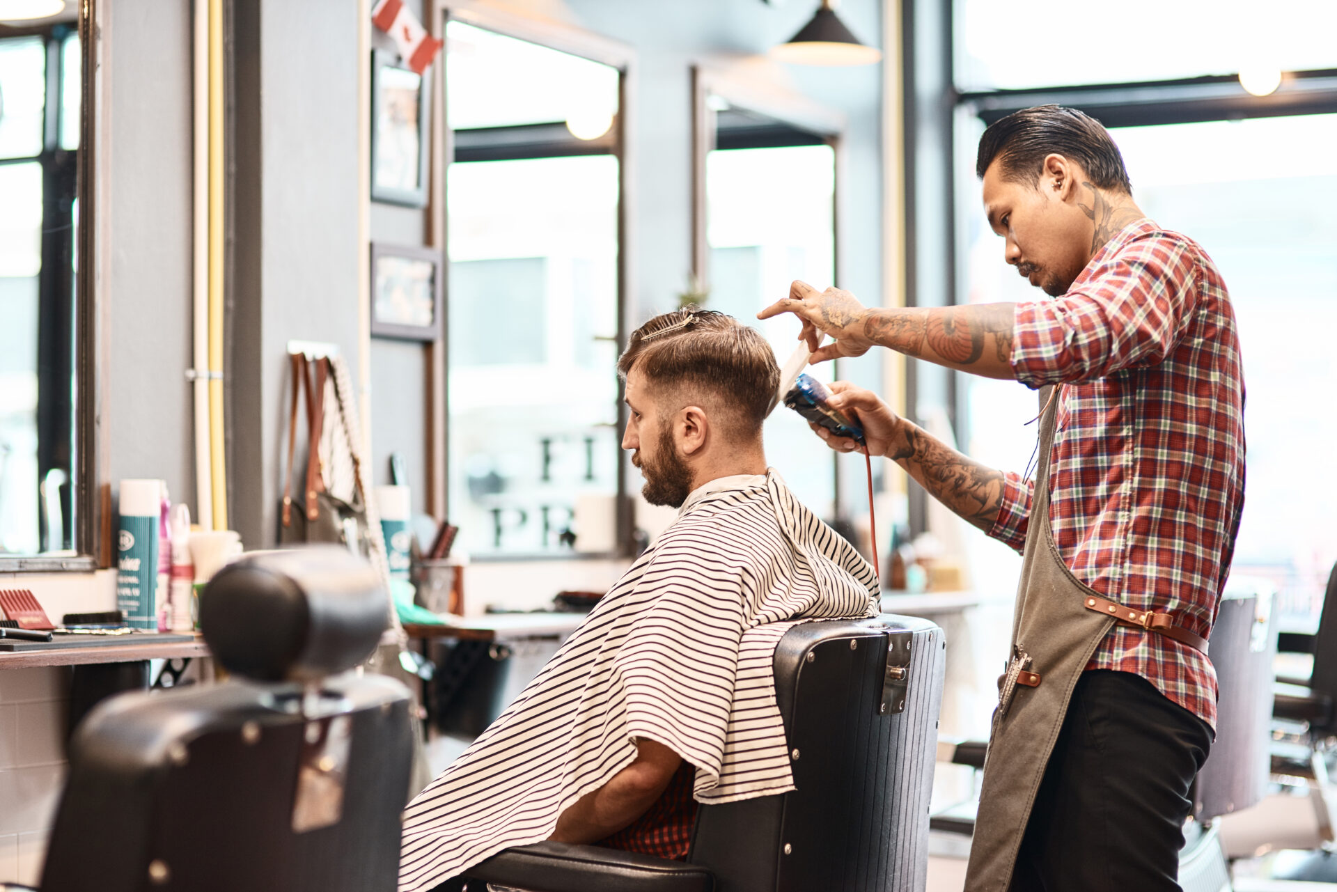 concentrated professional barber makgng a haircut for a bearded man