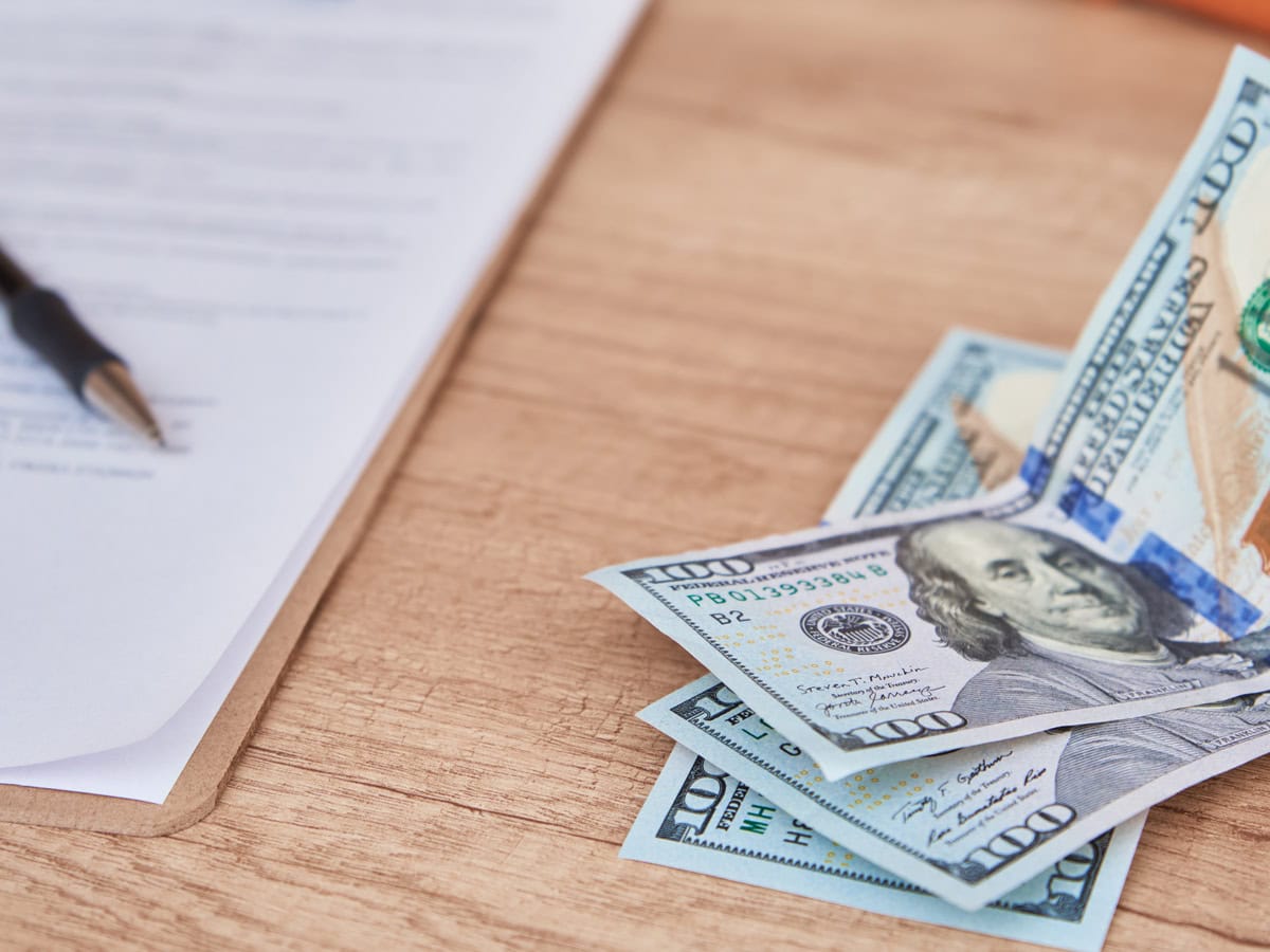 document, pen and dollar bills on table, close up