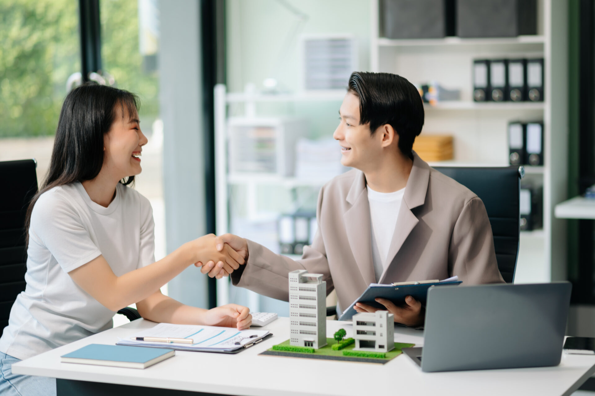 Real estate broker agent presenting and consult to customer to decision making sign insurance form agreement, home model, concerning mortgage loan offer in office