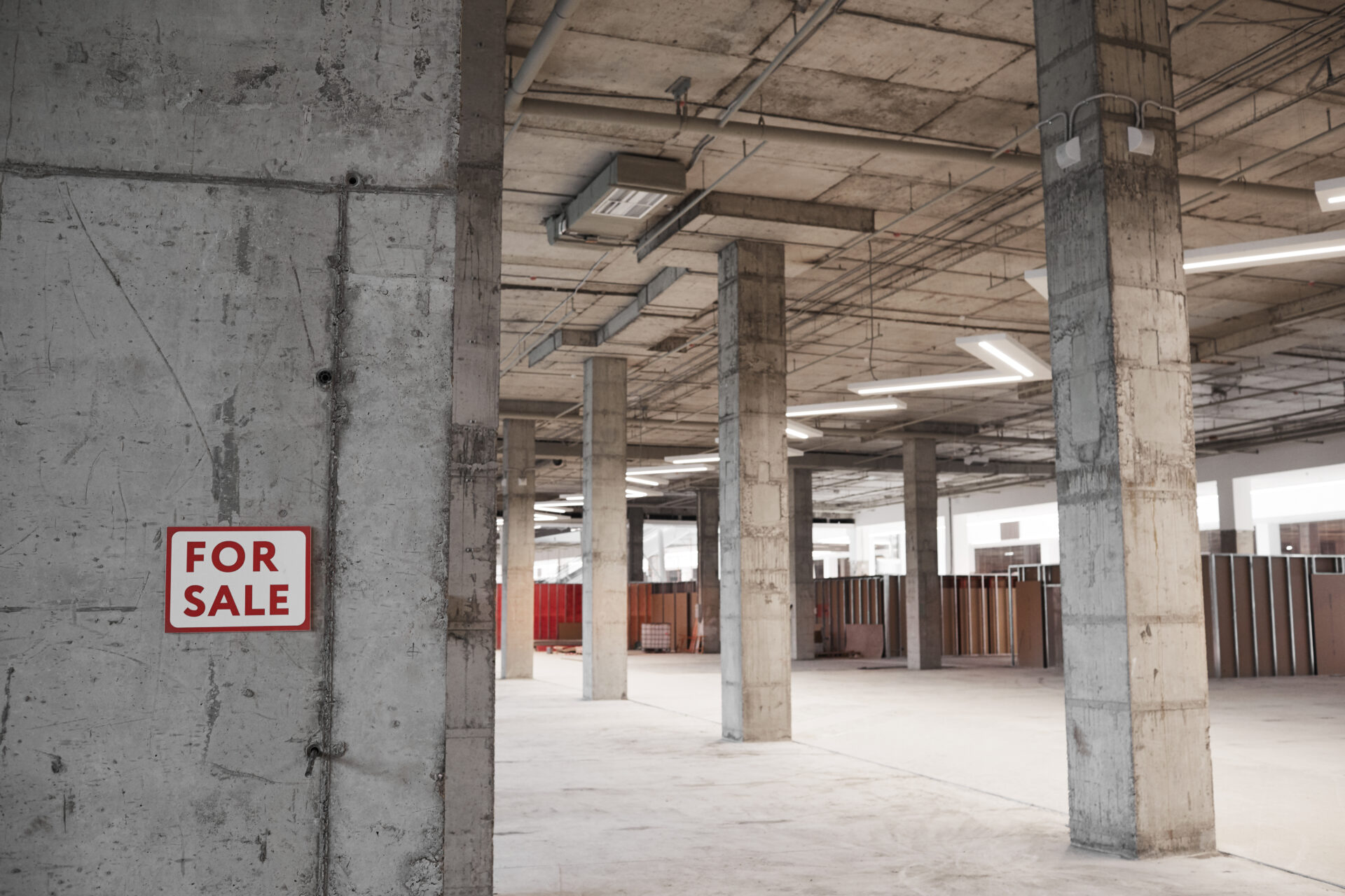 Background image of empty building under construction with concrete columns and For sale sign, copy space