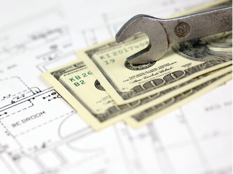 spanner on top of money with blueprints of residential house plan. restoring, repair, service maintenance cost