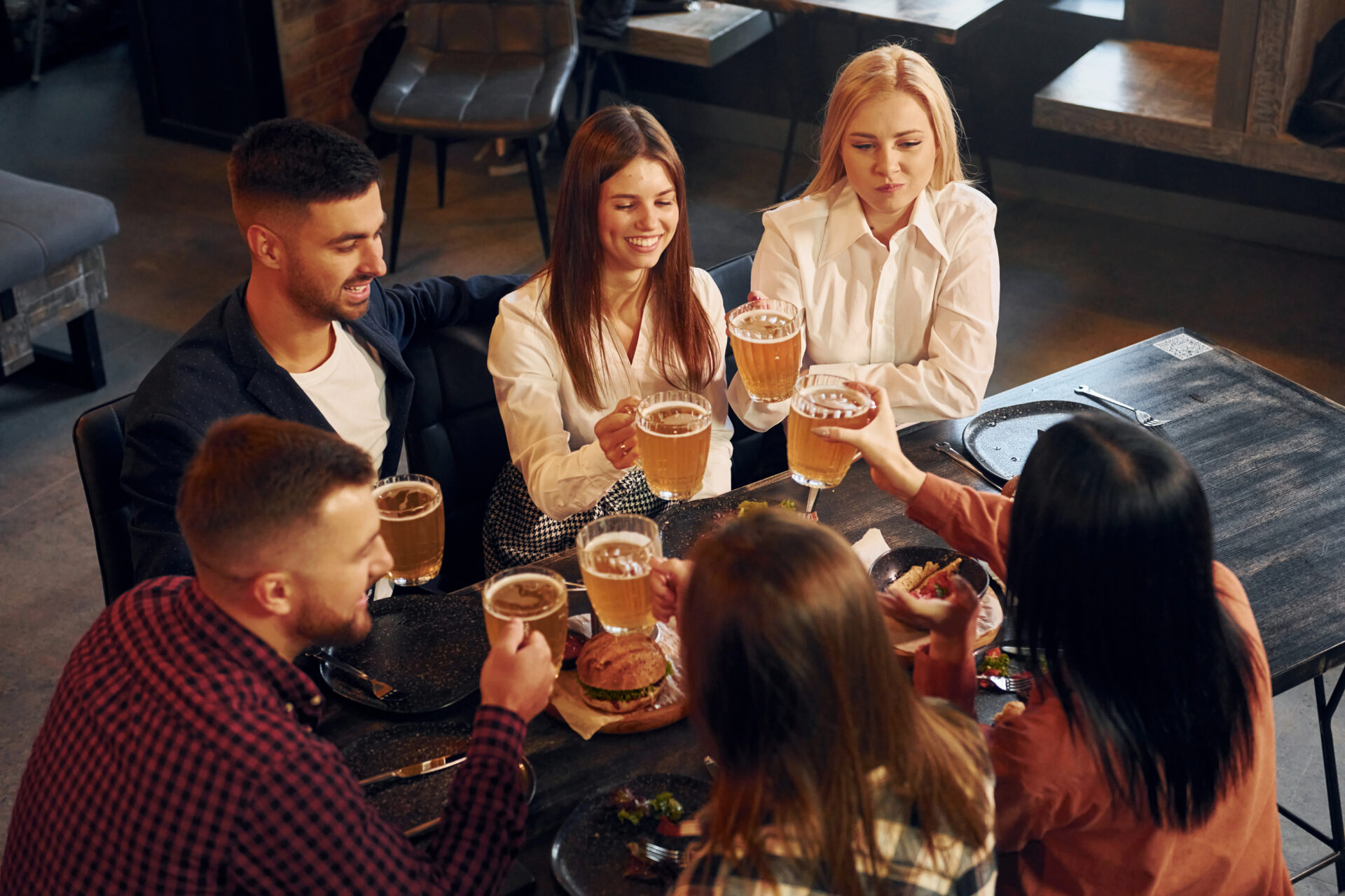 tasteful beer. group of young friends sitting together in bar