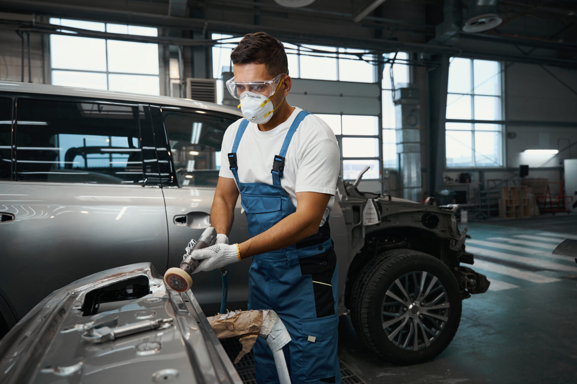 technician peel off old paint from car part