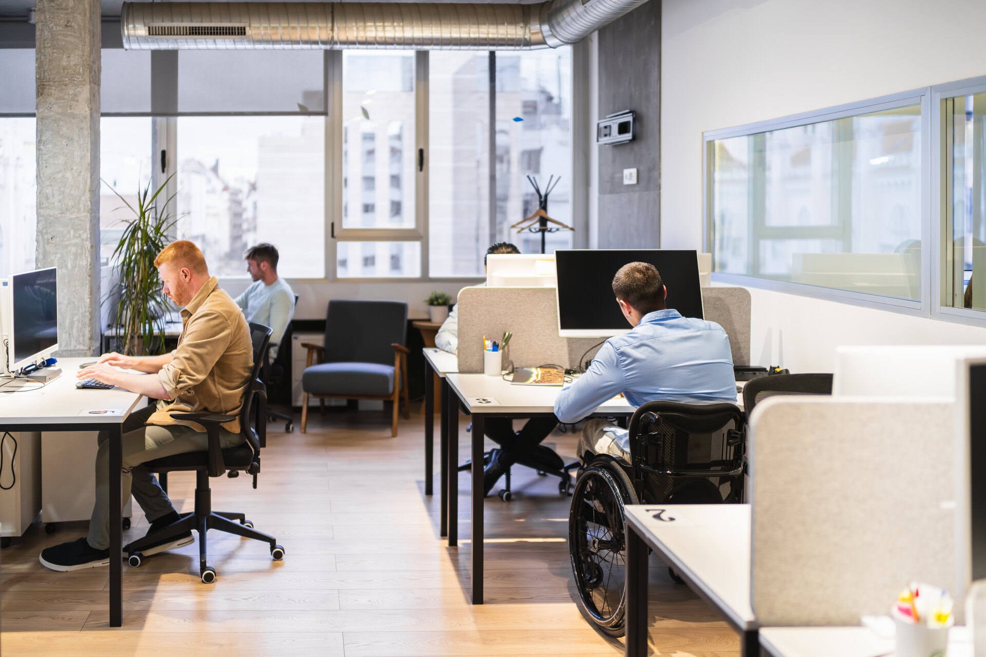 young professionals working in modern coworking space, including a person with disability . startup office lease in LA